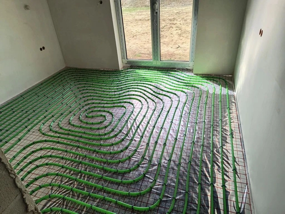 Układ zielonych rur ogrzewania podłogowego na izolacji termicznej w pomieszczeniu