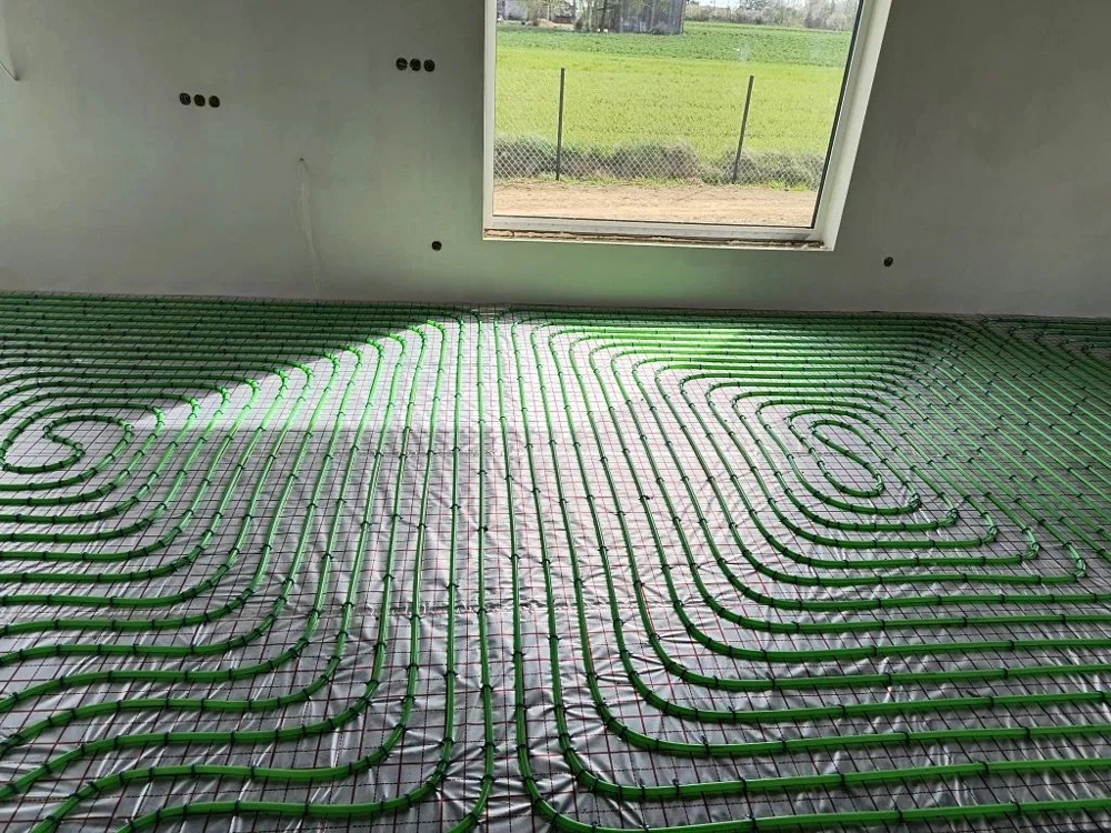 Instalacja ogrzewania podłogowego z zielonymi rurami na izolacji w pomieszczeniu